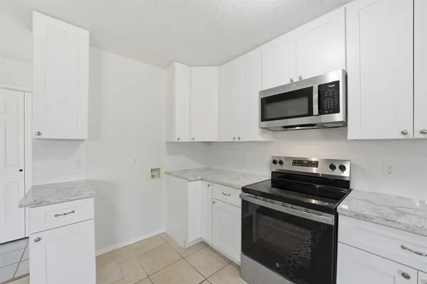 a kitchen with white cabinets and black appliances