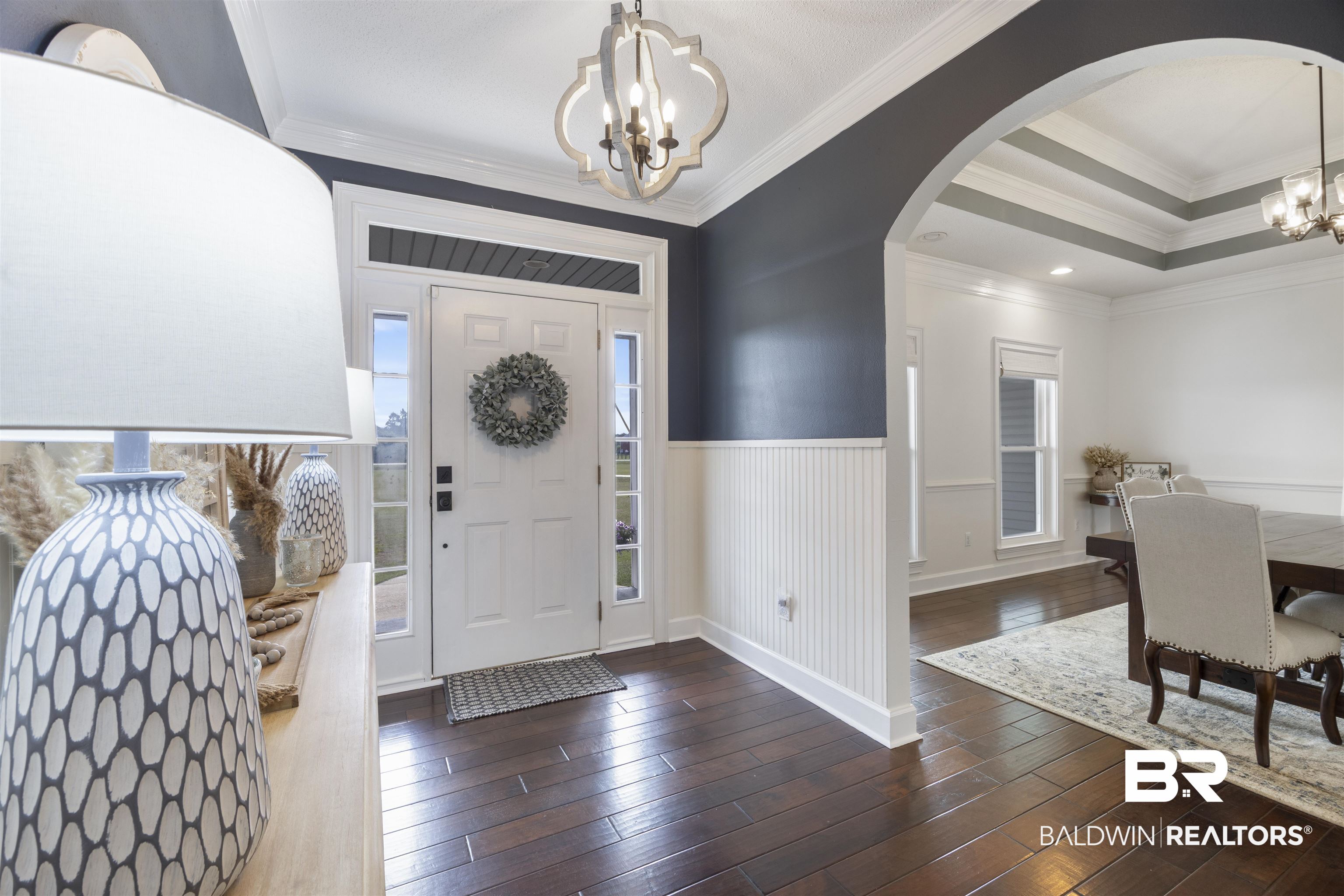 9855 Stucki Road Elberta, AL 36530 - Photo 9 of 54 Foyer entrance with suspended lighting, arched walkways, wainscoting, dark wood-type flooring, and crown molding