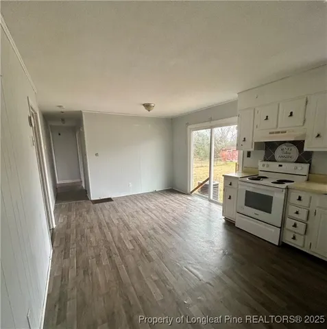 a kitchen with granite countertop a stove cabinets and wooden floor