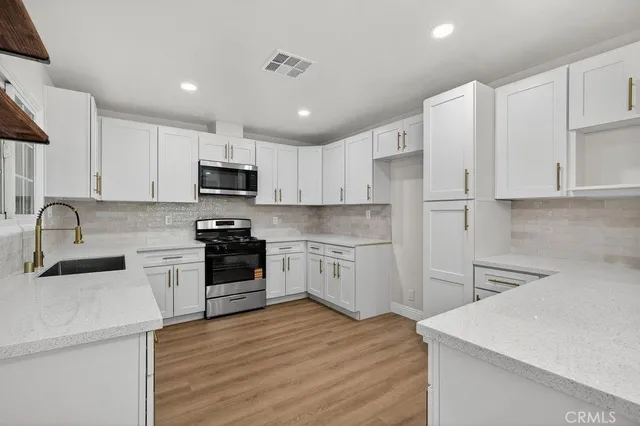 a kitchen with granite countertop white cabinets and stainless steel appliances