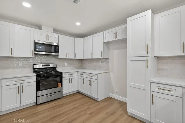 a kitchen with cabinets stainless steel appliances and a wooden floor