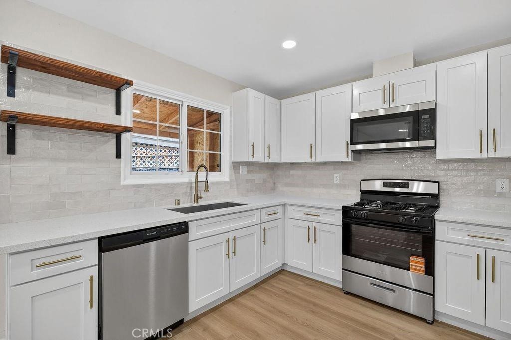 629 South Sage Avenue Rialto, CA 92376 - Photo 7 of 16 a kitchen with stainless steel appliances white cabinets and a stove top oven
