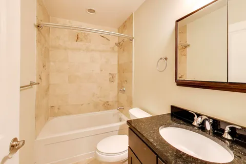 a bathroom with a granite countertop sink toilet and shower