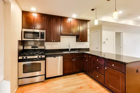a kitchen with stainless steel appliances granite countertop wooden cabinets a stove and a sink