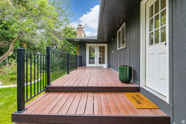 4150 Dover Lane Provo, UT 84604 - Photo 39 of 44 Expansive wood-finish deck with black metal railing, featuring a white paneled door with glass inserts and an additional set of white French doors