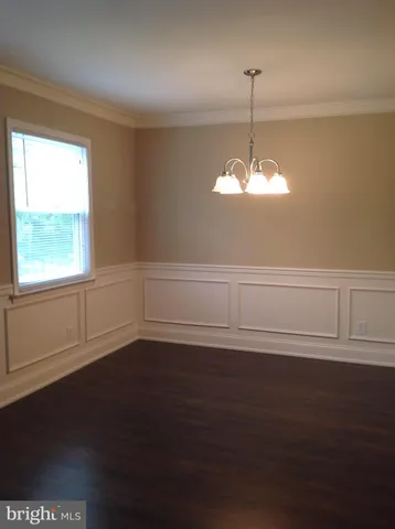 a view of a chandelier fan and wooden floor in an empty room