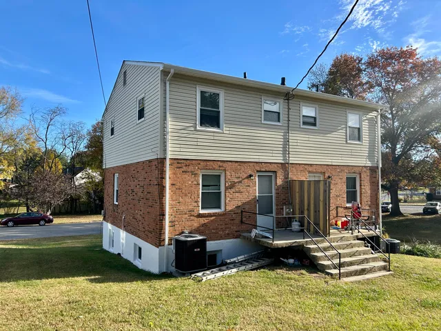 a view of house with yard outdoor seating and covered with trees