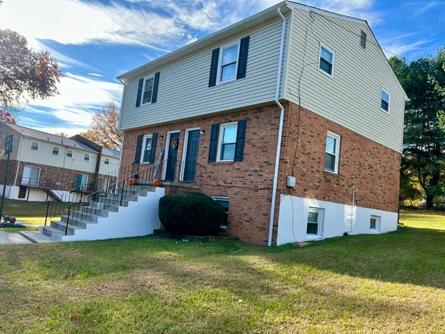 a view of a house with a yard and a large tree