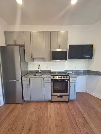 a kitchen with stainless steel appliances a stove a microwave and a hard wood floors