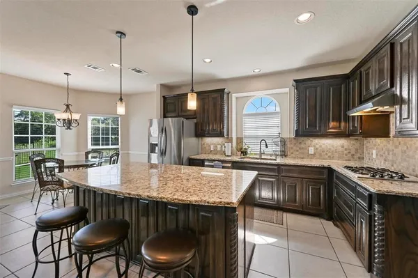 a kitchen with granite countertop a stove a sink a dining table and chairs