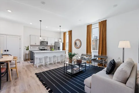 a living room with furniture kitchen view and a wooden floor