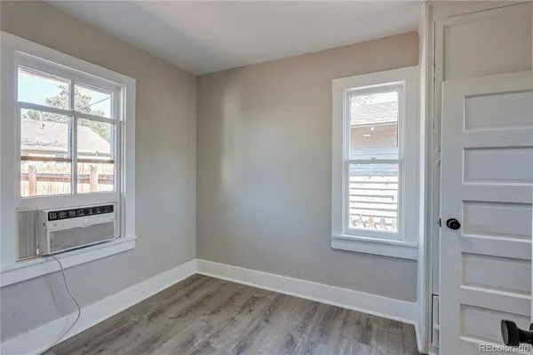 a view of an empty room with a window and wooden floor