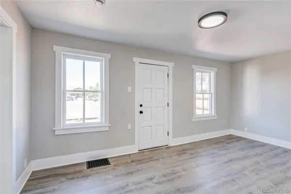 an empty room with wooden floor and windows