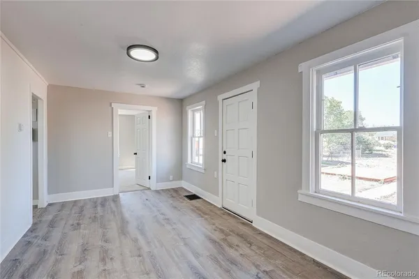 a view of an empty room with wooden floor and a window