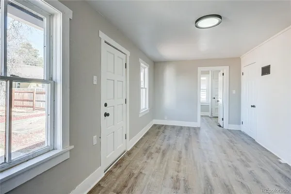 a view of an empty room with wooden floor and a window