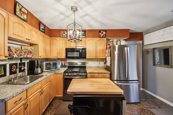 a kitchen with stainless steel appliances granite countertop a stove refrigerator and microwave