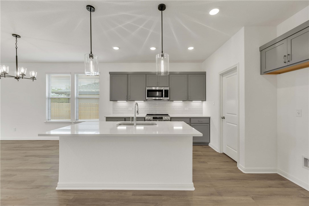 2776 Messenger Way Bryan, TX 77803 - Photo 4 of 16 a large kitchen with kitchen island a stove a sink a center island and wooden floor