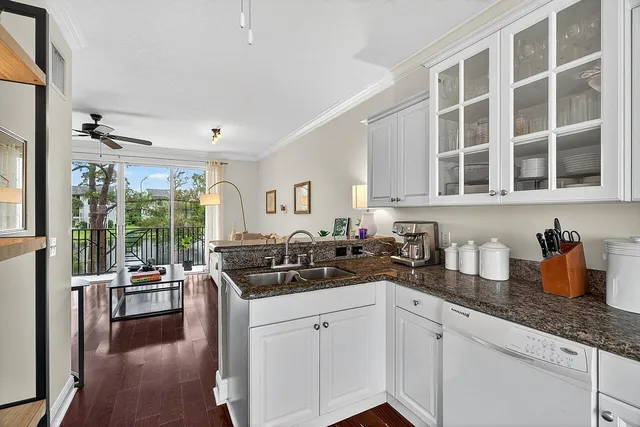 a kitchen with granite countertop a sink and white cabinets next to a window