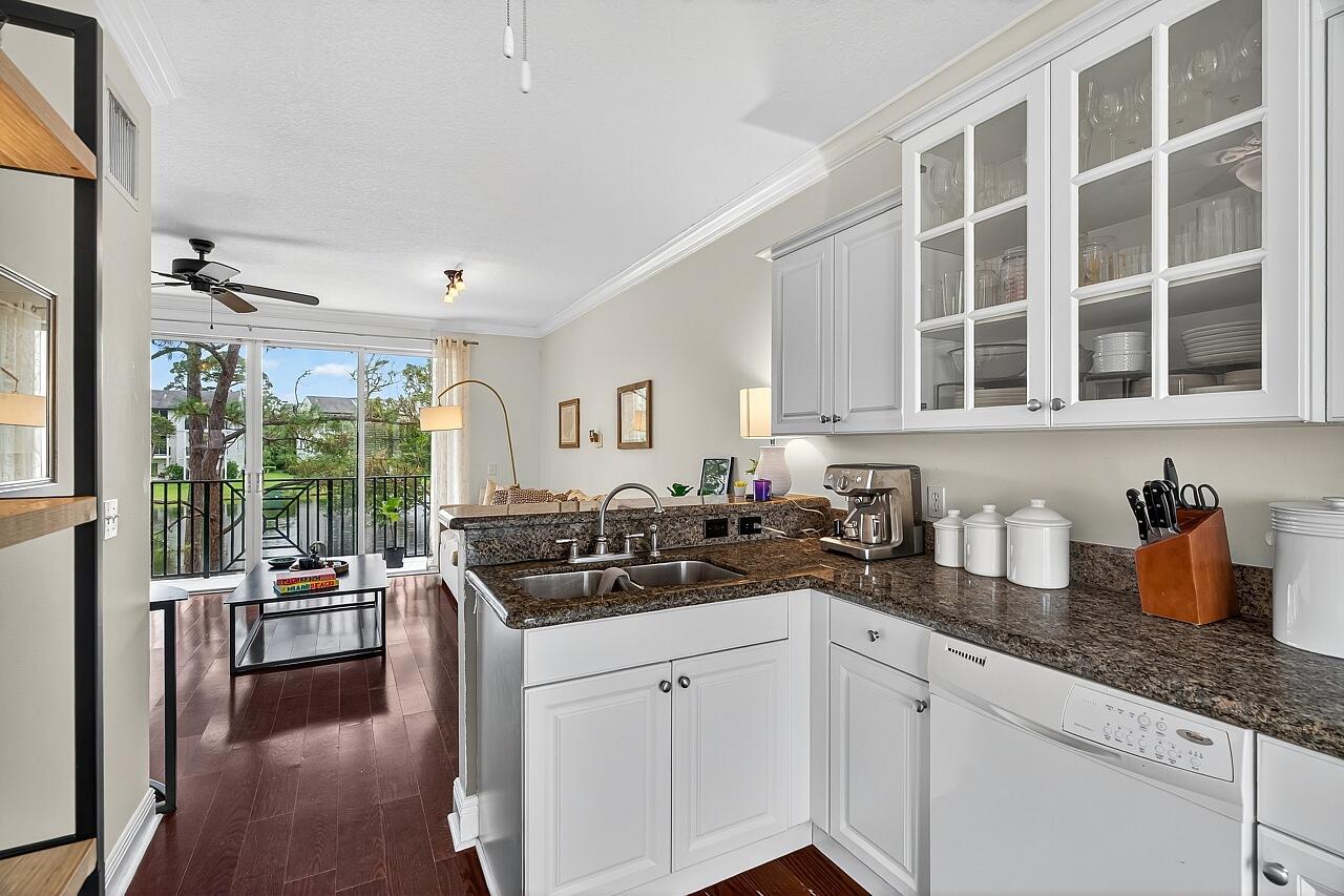 1685 42nd Square, Unit 101 Vero Beach, FL 32960 - Photo 14 of 37 a kitchen with granite countertop a sink and white cabinets next to a window
