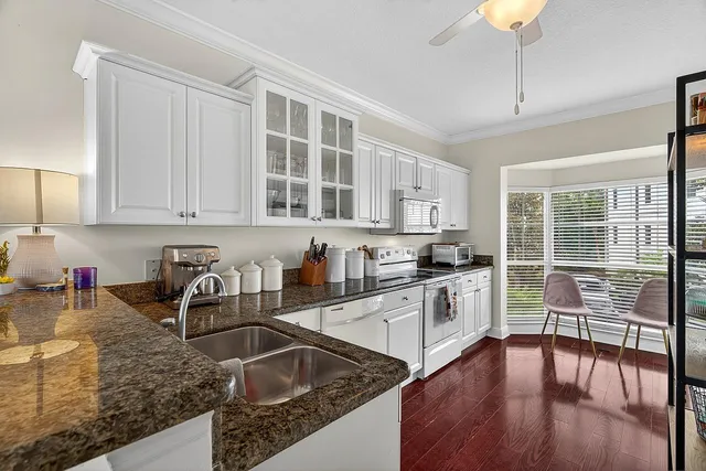 a kitchen with granite countertop a stove a sink a refrigerator and cabinets