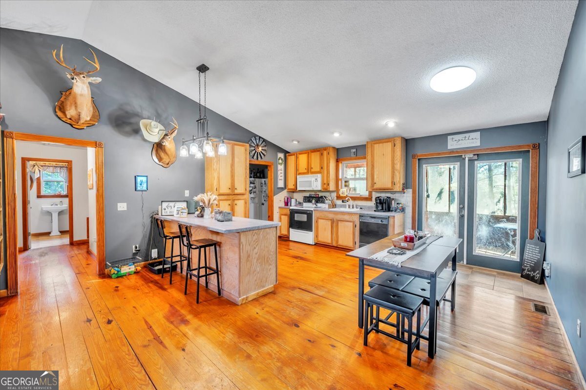874 Mistletoe Road Abbeville, GA 31001 - Photo 19 of 67 a large dining hall with stainless steel appliances granite countertop a stove oven a dining table and chairs with wooden floor