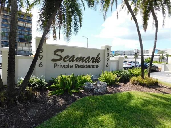 a sign of golf club on a wall under a tree