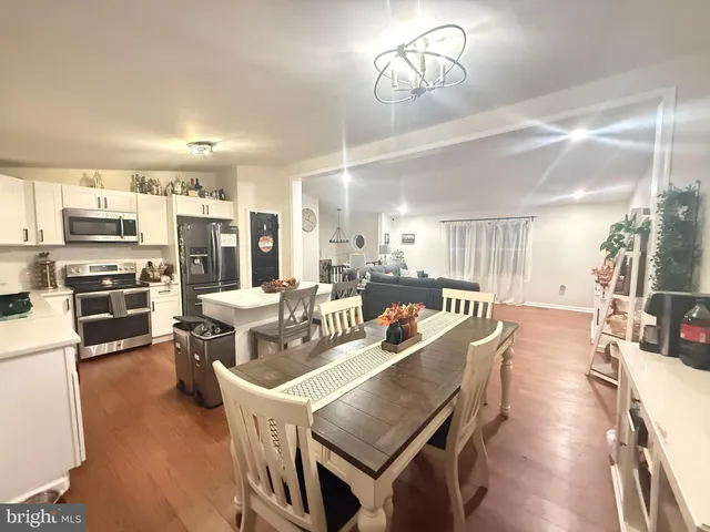 a living room with stainless steel appliances kitchen island granite countertop furniture a rug kitchen view and a chandelier