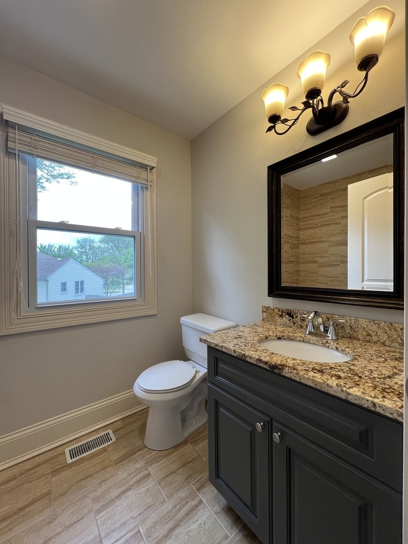 1108 Devonshire Road Buffalo Grove, IL 60089 - Photo 19 of 22 a bathroom with a granite countertop sink vanity mirror and toilet