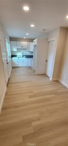 a view of kitchen and empty room with wooden floor