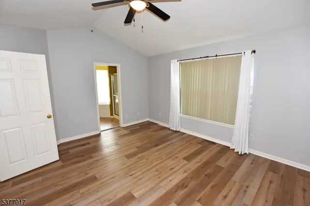 an empty room with wooden floor cabinet and windows