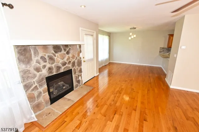 a view of empty room with wooden floor and fireplace