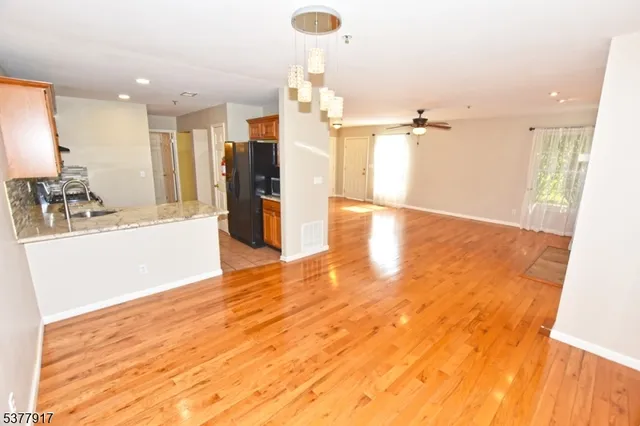 a view of a kitchen with kitchen island a sink wooden floor and a glass door shower