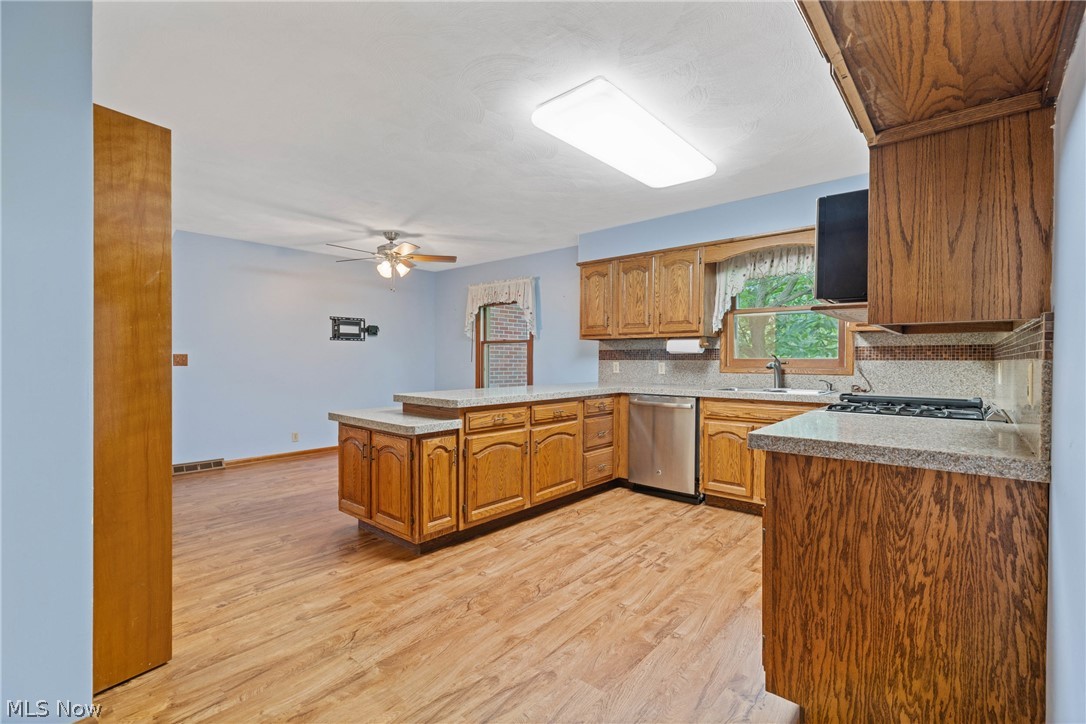 16295 Sperry Road Vermilion, OH 44089 - Photo 9 of 48 Kitchen with light hardwood / wood-style floors, kitchen peninsula, dishwasher, ceiling fan, and tasteful backsplash