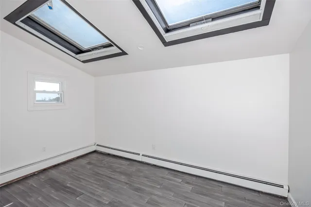 a view of an empty room with wooden floor and a ceiling fan