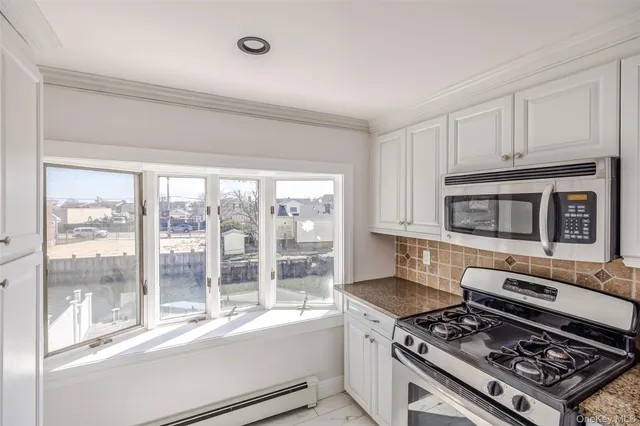 a kitchen with granite countertop a stove and a white cabinet