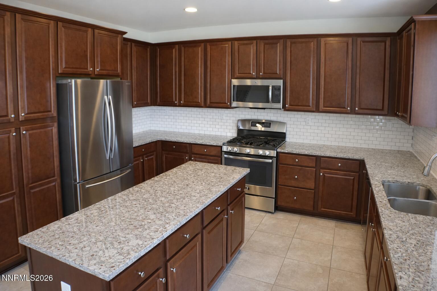 10855 Pebble Hill Drive Reno, NV 89521 - Photo 7 of 27 a kitchen with stainless steel appliances granite countertop a stove refrigerator sink and microwave