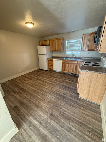 102 East Richelman Lane Wellington, UT 84542 - Photo 5 of 14 Kitchen with wood-finish flooring, wood cabinetry, stone-look countertops, and white appliances