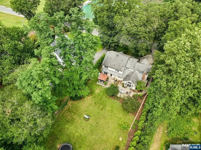 an aerial view of residential house with outdoor space and trees all around
