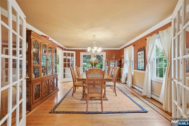 a dining room with wooden floor and large windows