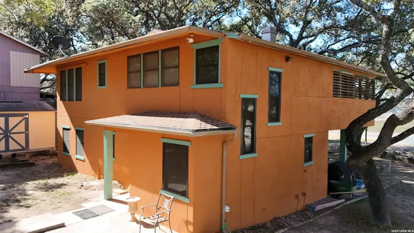 a backyard of a house with large trees and parked