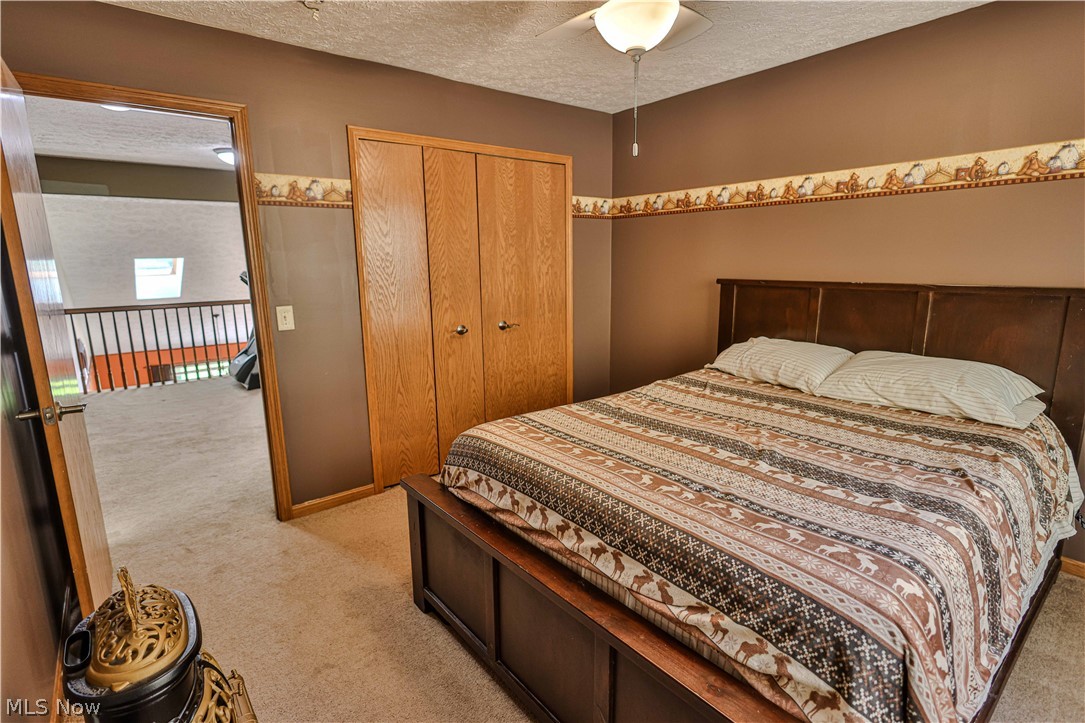 11154 Johnsford Road Southwest Beach City, OH 44608 - Photo 39 of 50 Bedroom featuring a ceiling fan with integrated lighting, built-in closet with natural wood doors, and a neutral carpeted floor
