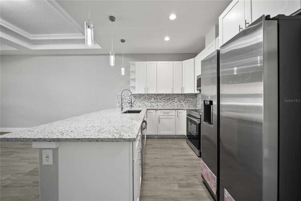 98 Wheatfield Drive, Unit B Palm Coast, FL 32164 - Photo 4 of 21 a kitchen with stainless steel appliances granite countertop a refrigerator sink and cabinets