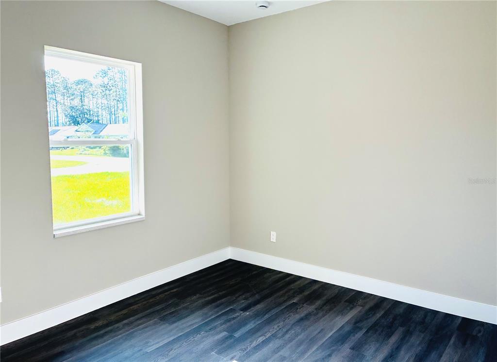 98 Wheatfield Drive, Unit B Palm Coast, FL 32164 - Photo 7 of 21 a view of an empty room with wooden floor and a window
