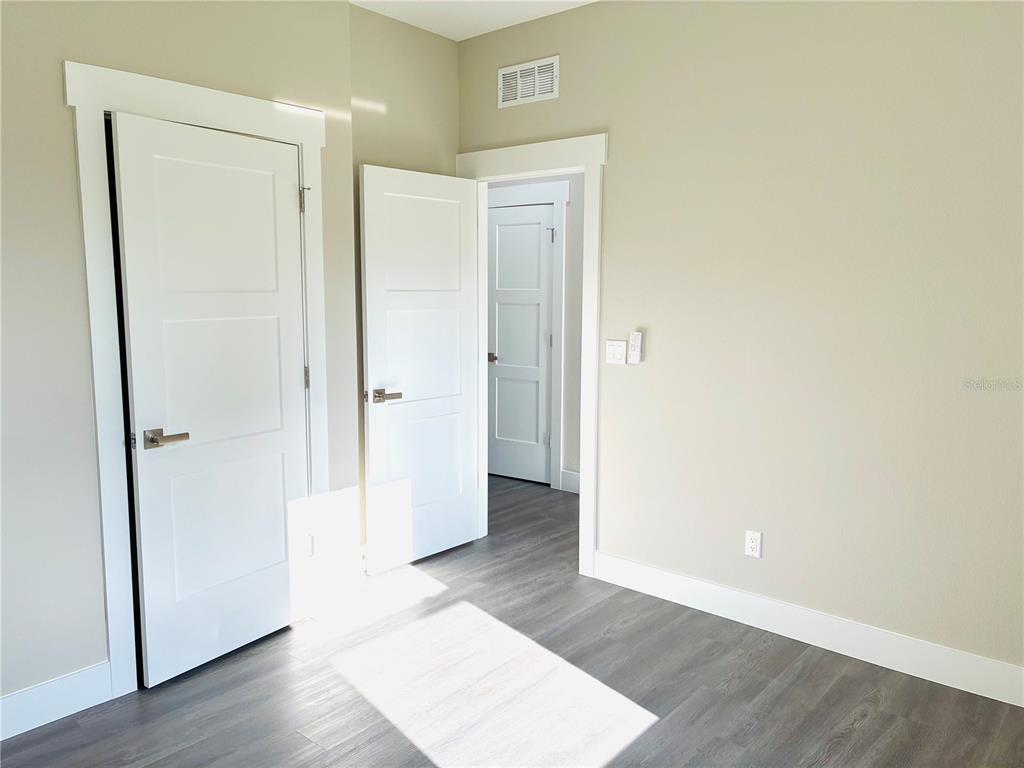 98 Wheatfield Drive, Unit B Palm Coast, FL 32164 - Photo 8 of 21 an empty room with wooden floor and a bathroom