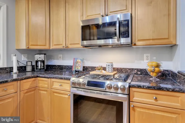 a kitchen with granite countertop a refrigerator and a stove top oven