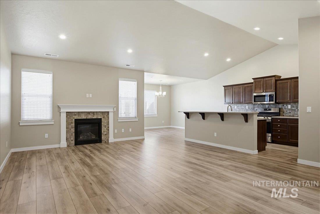 12460 West Azure Street Boise, ID 83713 - Photo 6 of 34 Open-concept living area featuring a vaulted ceiling and wood-finish flooring