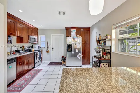 a kitchen with stainless steel appliances kitchen island granite countertop a refrigerator and a sink
