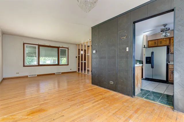 a view of an empty room with window and wooden floor