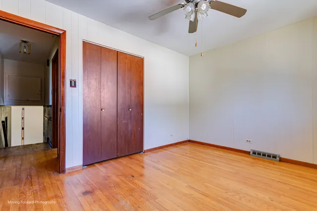 a view of empty room with wooden floor and fan