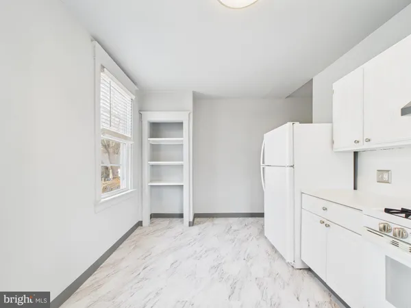 a view of a kitchen with refrigerator and white cabinets